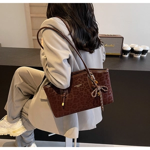 Détail du sac cabas léopard avec breloque en corde tressée sur un tailleur gris