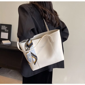 Detailed view of cream tote bag with silk scarf on a model wearing a black blazer