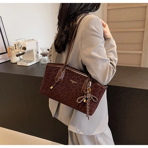 Détail du sac cabas léopard avec lanières en cuir marron et pendentif dans un café