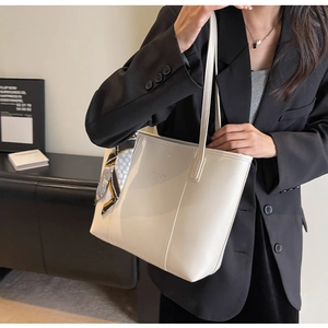 Detail view of cream leather tote bag with silk scarf on handle and shoulder strap