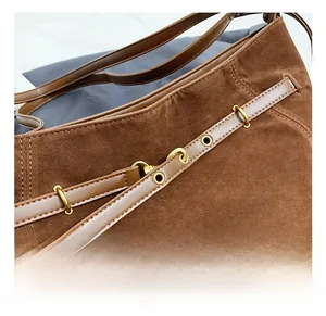 Detail of dark brown suede bag with smooth leather straps and vintage gold hardware