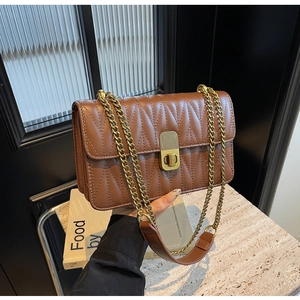 Detail of a brown quilted chain bag with gold hardware and V-pattern stitching