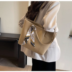 Detail of khaki leather tote bag with printed silk scarf on a shoulder-wearing model