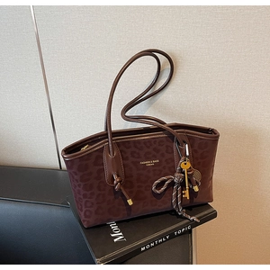 Détails d'un sac cabas léopard avec porte-clés doré et pompon tissé élégant