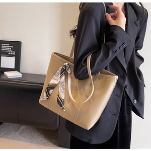 Detail of khaki leather tote bag with elegant silk scarf and gold lettering