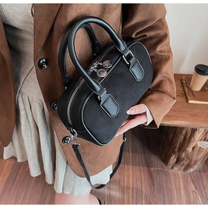 Detail der schwarzen Wildleder-Boston-Bag mit Lederbesatz, getragen von einem Modell