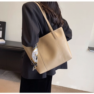 Large khaki tote bag with fashion lettering and decorative scarf shown on shoulder