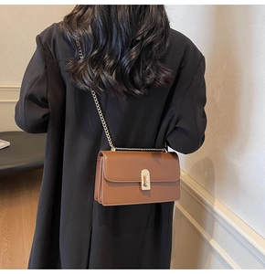 Detailed view of a brown vintage leather crossbody bag with a gold metal chain strap