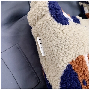 Close-up of fuzzy shearling bucket bag texture with blue and brown geometric patterns