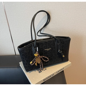 Gros plan d'un sac cabas noir à motif léopard avec logo doré et pendentif élégant