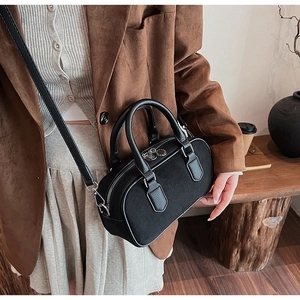 Close-up of black leather and suede pillow bag worn as a shoulder bag on a model