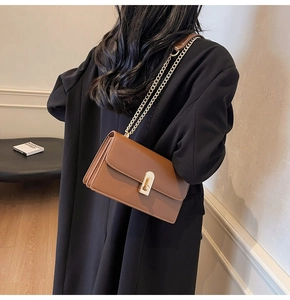 Brown leather crossbody bag detail featuring gold chain strap and elegant twist lock