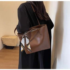 Detail of a large dark brown faux leather tote bag with a decorative floral silk scarf