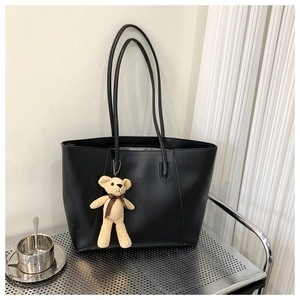 Detail of a black large-capacity PU leather tote bag with a cute teddy bear charm