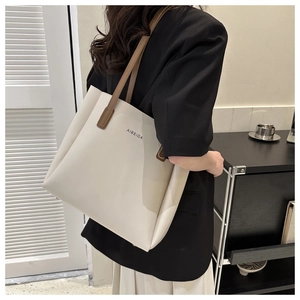 Detail shot of a cream tote bag with dark brown handles and smooth leather texture