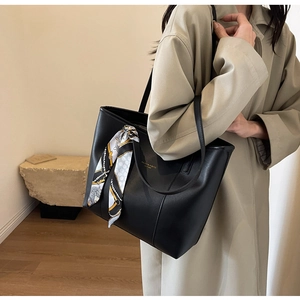 Side view of black leather tote bag with elegant silk scarf and gold lettering on model