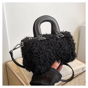 Detail of plush black wool mini bag featuring smooth leather handles and silver hardware
