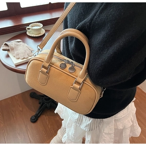 Detail view of ginger yellow boston bag with lychee texture and silver dual zippers