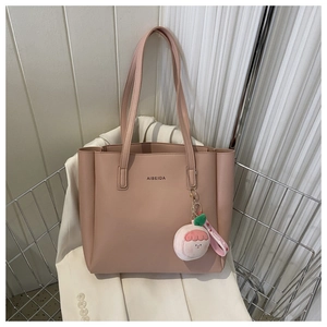 Close-up of pink faux leather tote bag texture with brand logo and cute charm detail