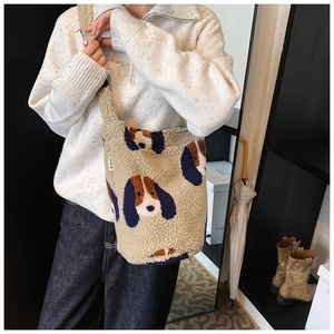 Plush beige bucket bag with polka dot dog pattern worn as a crossbody style
