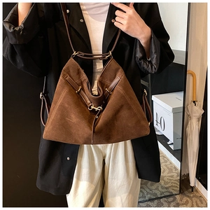 Macro detail of large brown suede tote bag with triangular fold design and metal buckles