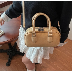 Detail einer ingwergelben Boston Bag mit Lederstruktur und Doppelreißverschluss