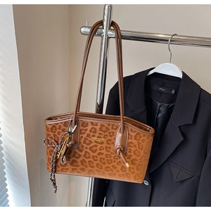 Détail d'un cabas léopard avec logo doré et pendentif métallique noué élégant