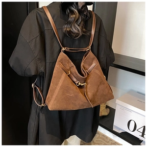 Detail view of deep brown suede backpack with vintage bronze buckles on woman model