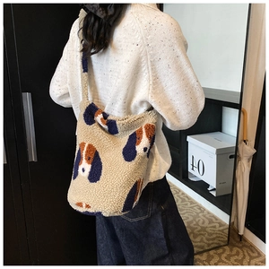 Detail of plush crossbody bag featuring cute cartoon dog patterns on beige faux shearling