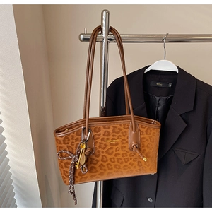 Gros plan d'un sac cabas léopard avec lettrage doré et pendentif décoratif à clé
