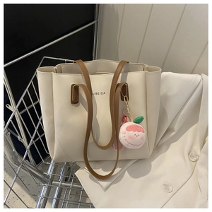 Cream tote bag with brown straps and peach plush charm in a metal cart