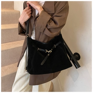 Close-up of black suede tote bag featuring premium leather straps and gold metal buckle