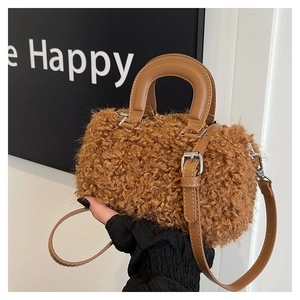 Detail of curly teddy faux fur texture and leather handle on brown cylinder bag