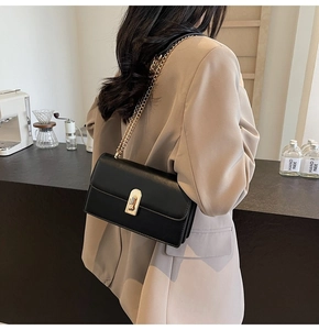 Chic black leather shoulder bag with gold chain strap shown on model in cafe