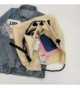 Spacious interior of beige drawstring tote showing storage for tablet and umbrella