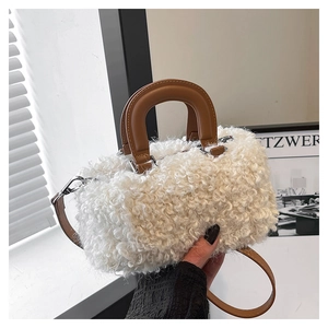 Detail of white faux fur mini handbag with brown leather handle and silver metal buckles
