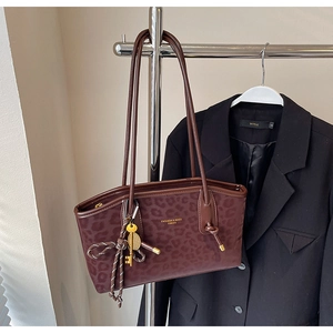Détail du sac cabas léopard avec breloque clé dorée et ruban nœud sur un cintre