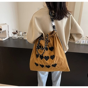 Detail of caramel large capacity bag with black pixel heart patterns and braided strap