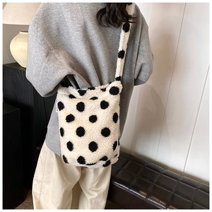 Chic white fuzzy faux fur shoulder bag with black polka dots shown on a model