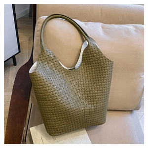 Gros plan du sac cabas tressé vert olive sur canapé montrant sa texture fine et son volume