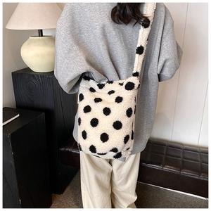 Detail of plush lamb wool bucket bag with large black polka dots and wide strap