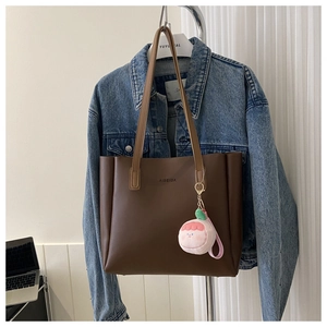 Detailed view of a brown matte tote bag with AIBEIDA logo and a pink plush charm decor