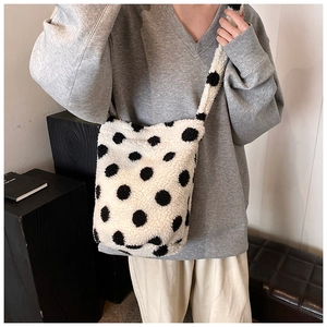 Close-up of white plush polka dot bucket bag showing soft shearling texture and wide strap