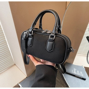 Detail of a black mini pillow bag with matte texture and dual zipper closures