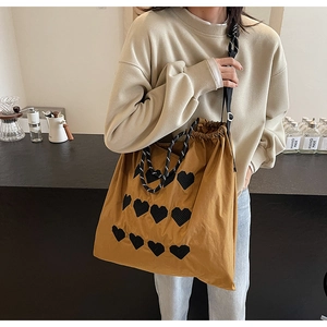 Detail of embroidered heart patterns on mustard yellow tote bag with patterned strap