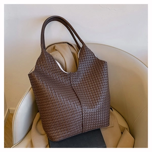 Gros plan sur un sac cabas tressé marron foncé avec texture de cuir détaillée