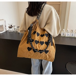 Detail of caramel tote bag with black 3D hearts and thick woven rope handle