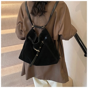 Detail of a large black matte backpack with drawstring and golden buckle on a model