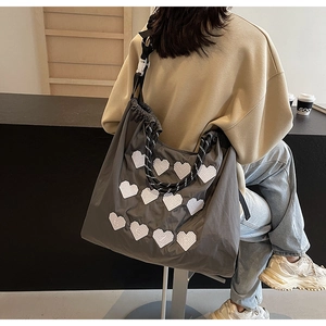 Detailed back view of a grey embroidered nylon tote bag with heart patches and rope straps