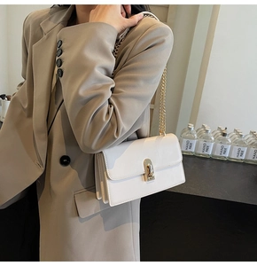 Detail of white leather shoulder bag with gold clasp and elegant chain strap on a model